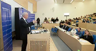 איש מדבר על פודיום והקהל מקשיב