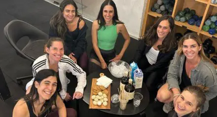 נשים מחייכות סביב שולחן שעליו אוכל