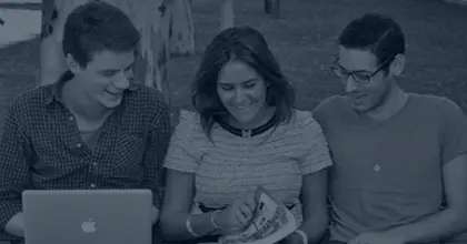3 סטודנטים מחייכים ומסתכלים על עיתון