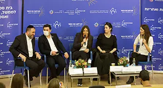 אנשים יושבים על כסאות על במה בפאנל