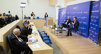 אנשים יושבים על כסאות על במה בפאנל