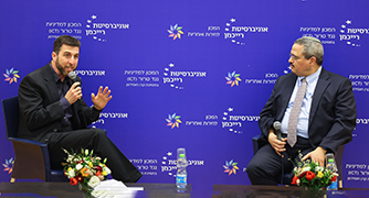 שני אנשים יושבים על כסאות על במה עם מיקרופונים
