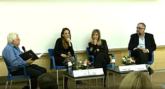 אנשים יושבים על כסאות על במה בפאנל
