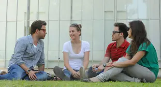 ארבעה אנשים יושבים על הדשא ומחייכים