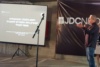 איש עומד על במה ומרצה
