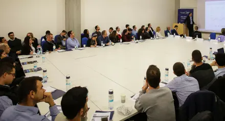 אנשים יושבים מסביב לשולחן ומסתכלים על המצגת 