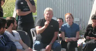 מדריך יושב על כיסא ומסביר משהו ומסביבו אנשים מקשיבים