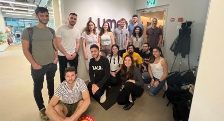 students standing in front of LUMEN company logo